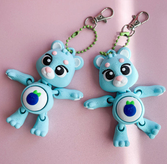Two blue cartoon character keychains on a pink background