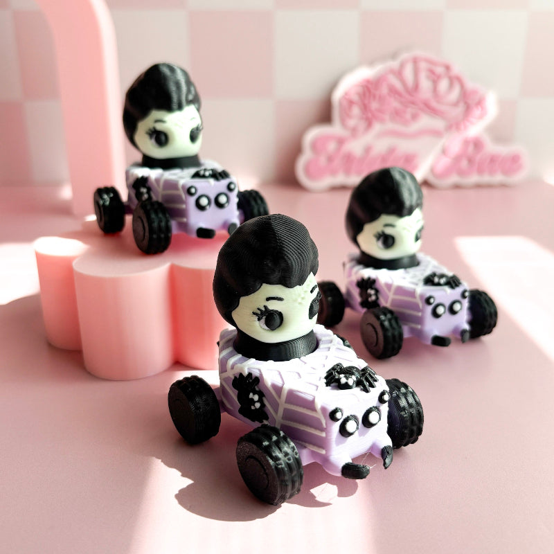 Three small toy cars with figurine fidget clicker with skeleton characters on a pink checkered background