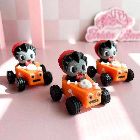 Three small toy cars with figurine fidget clicker with skeleton characters on a pink checkered background