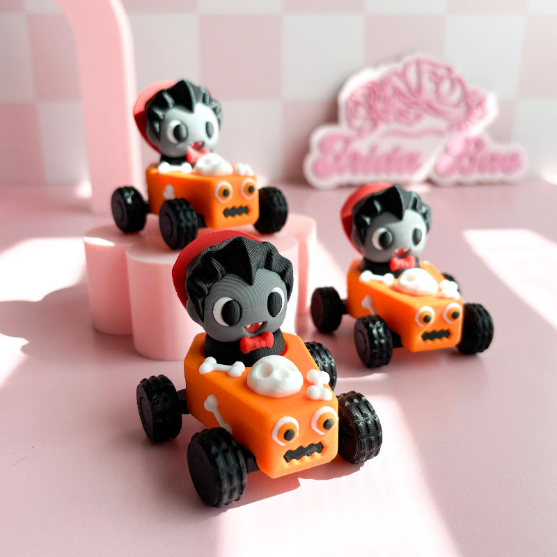 Three small toy cars with figurine fidget clicker with skeleton characters on a pink checkered background