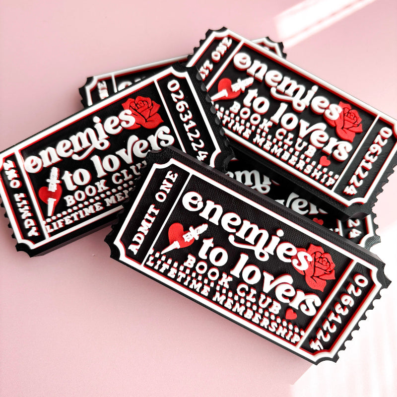 Three 'Enemies to Lovers' book club membership tickets on a pink background