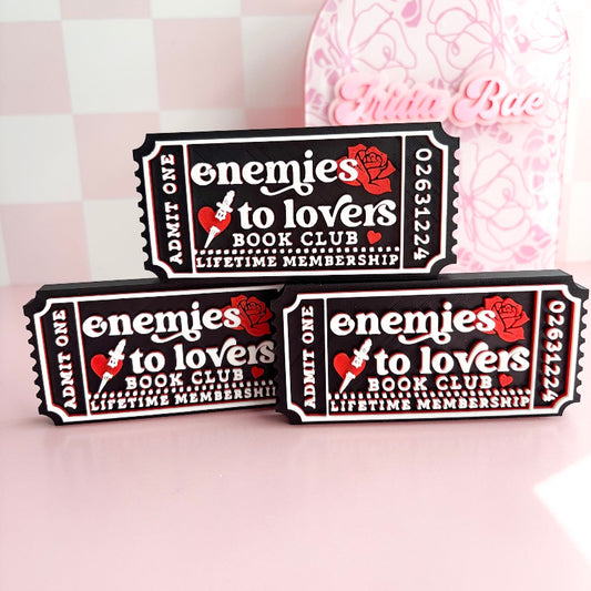 Three 'Enemies to Lovers' book club membership cards on a pink background