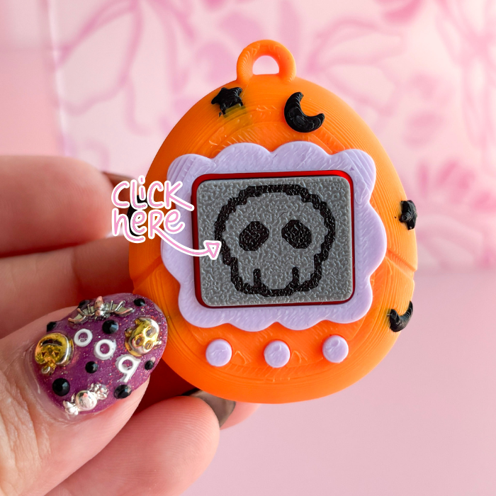 Orange toy with a skull design held by a hand against a pink background