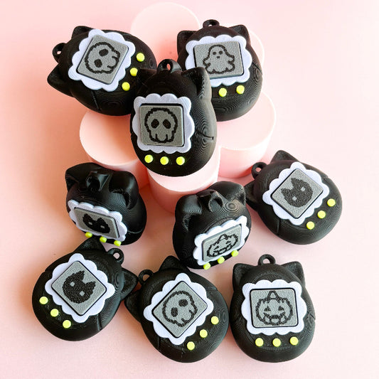 Black cat-shaped charms with skull designs on a pink background