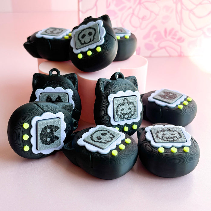 Black cat-shaped charms with white faces on a pink background