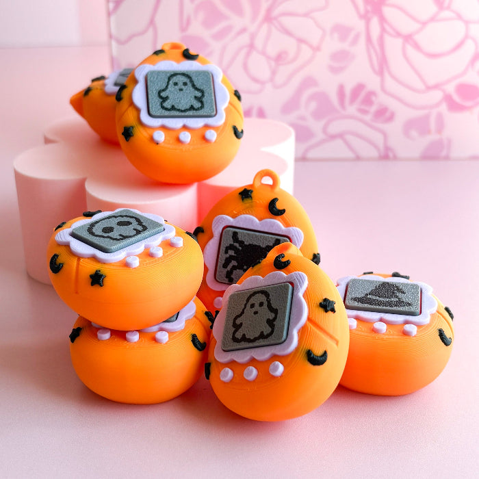 Orange toy devices with ghost face designs on a pink background