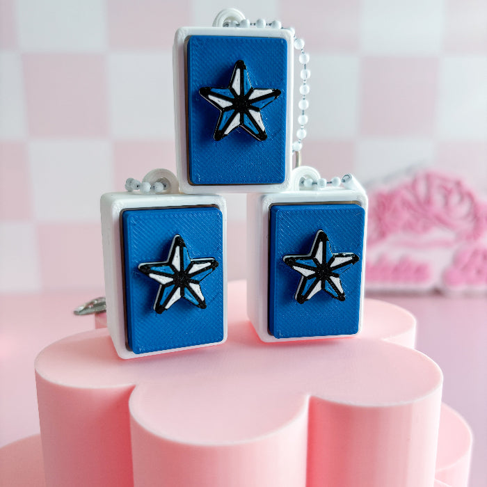 Mexican loteria fidget clicker with star designs on a pink stand against a pink and white checkered background