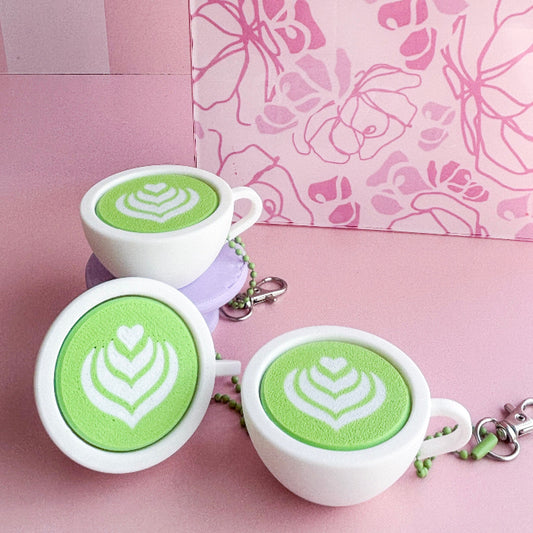 White ceramic cups with green latte art on a pink background