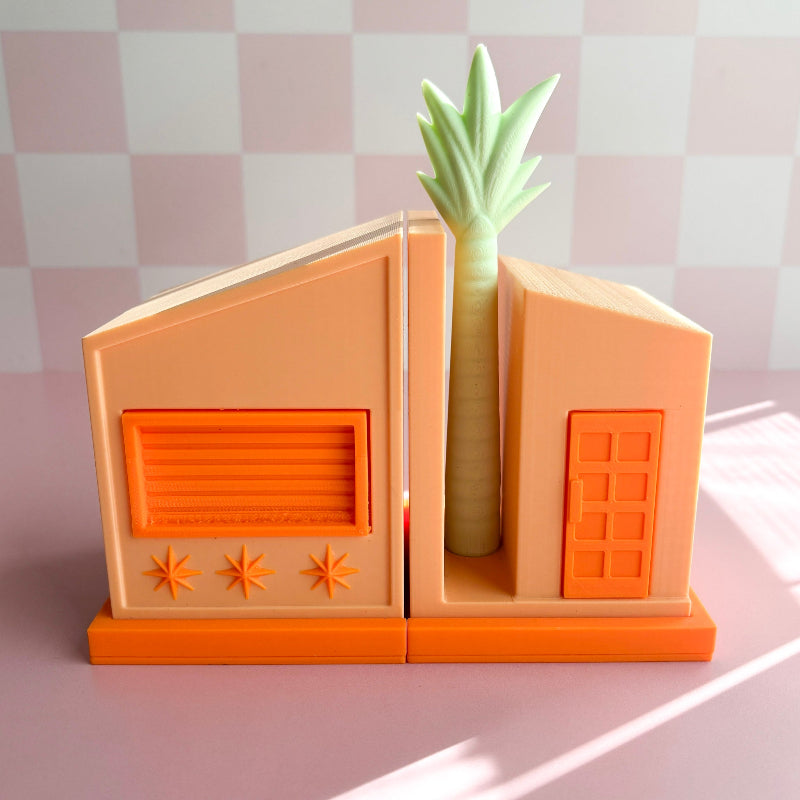 Bookend with house design holding a green plant against a checkered background