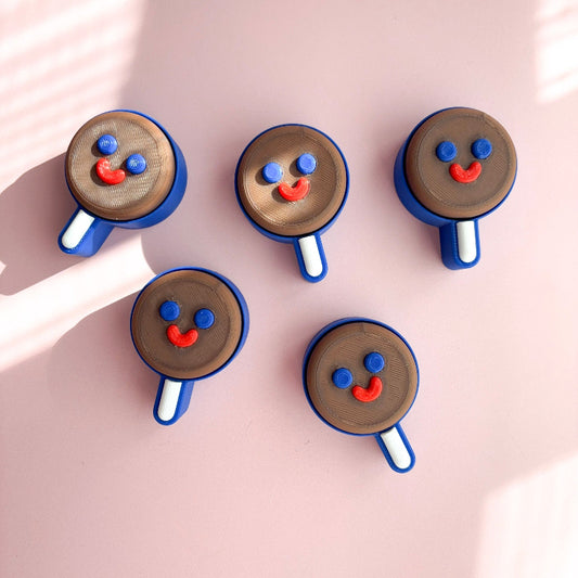 Five ice cream cone-shaped cookies with face designs on a pink background