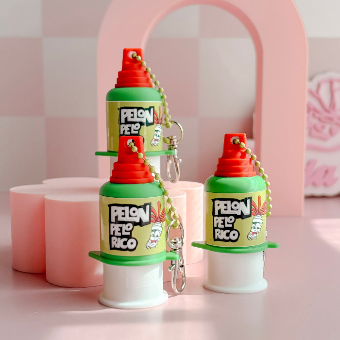Three colorful plastic containers clickers with red lids and 'Pelon Peló Rico' branding on a pink background.