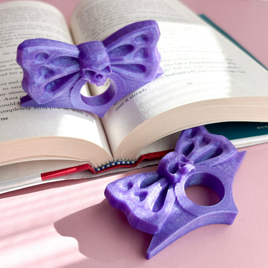 Purple bow-shaped bookmarks on an open book with a pink background