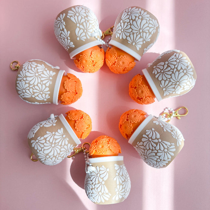 Decorative items with floral patterns and orange centers on a pink background