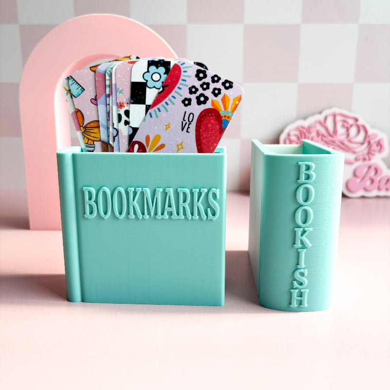Turquoise holder with colorful bookmarks and a smaller turquoise holder with 'BOOKISH' text on a pink background.