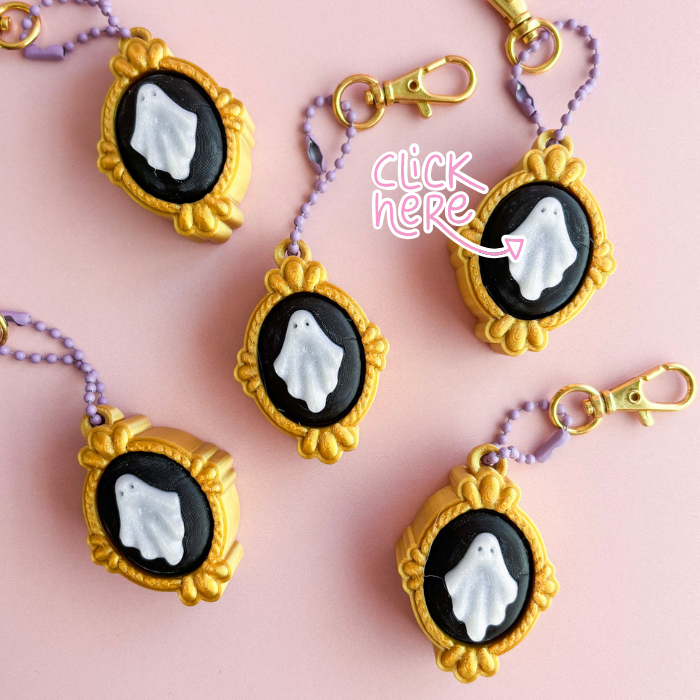 Ghost keychains in gold frames on a pink background with 'click here' text.