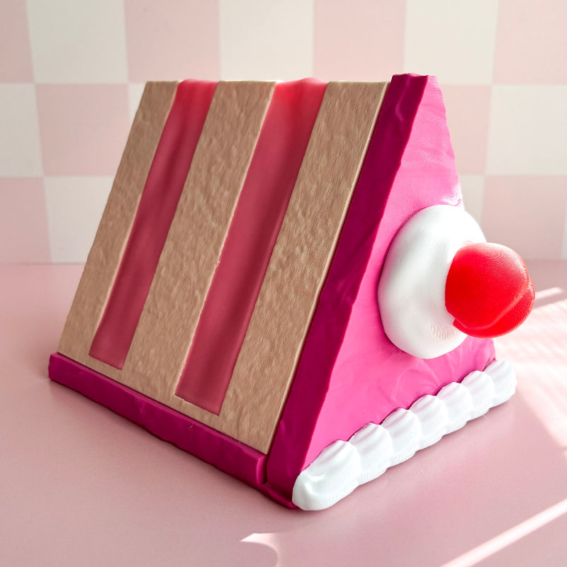 Book-shaped cake with a cherry on a pink surface