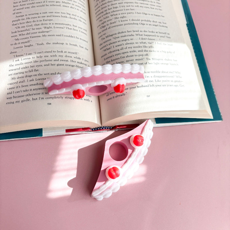 Pink book holder with red buttons on an open book