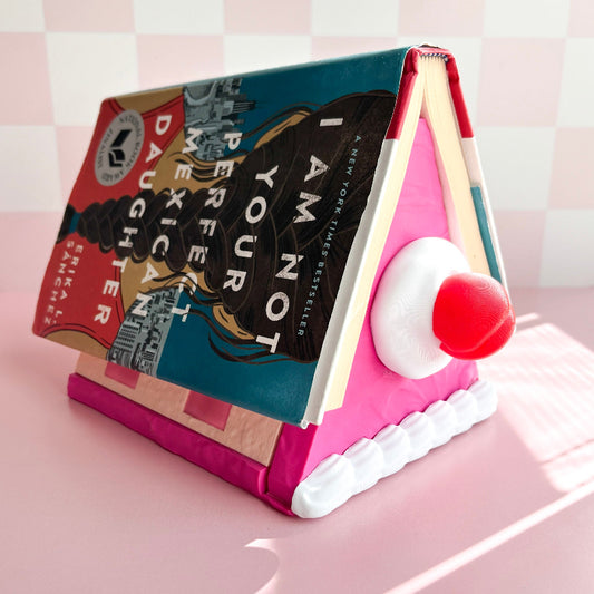 Book-shaped cake with a cherry on a pink surface