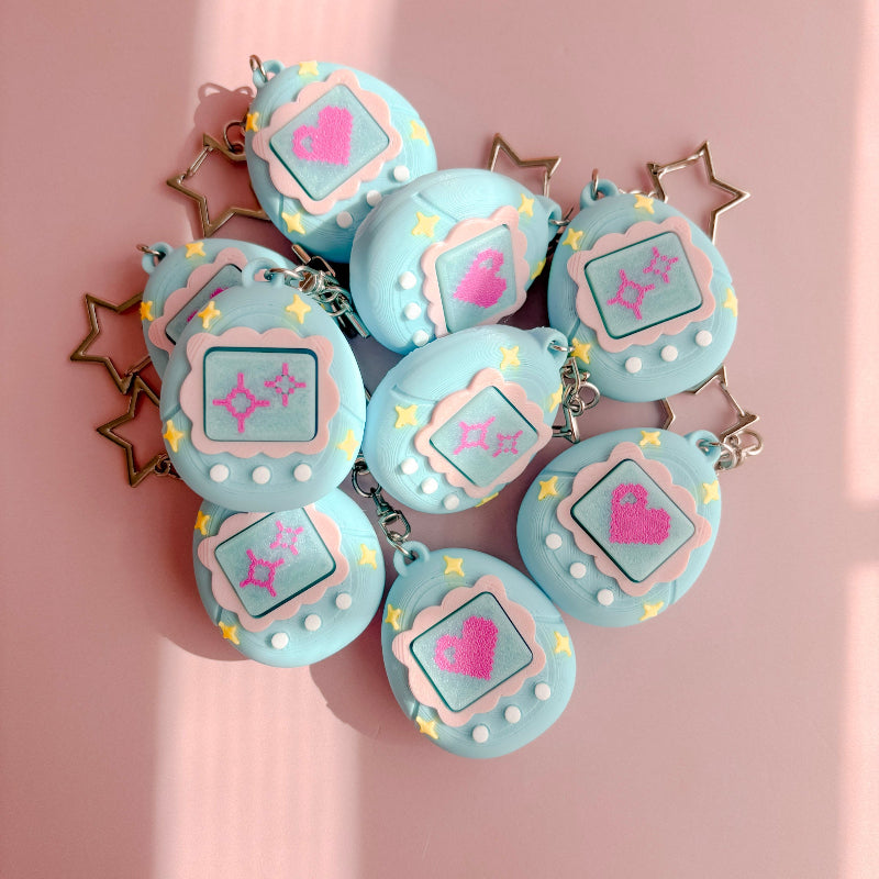 Set of blue VPet fidget clickers with heart designs on a pink background