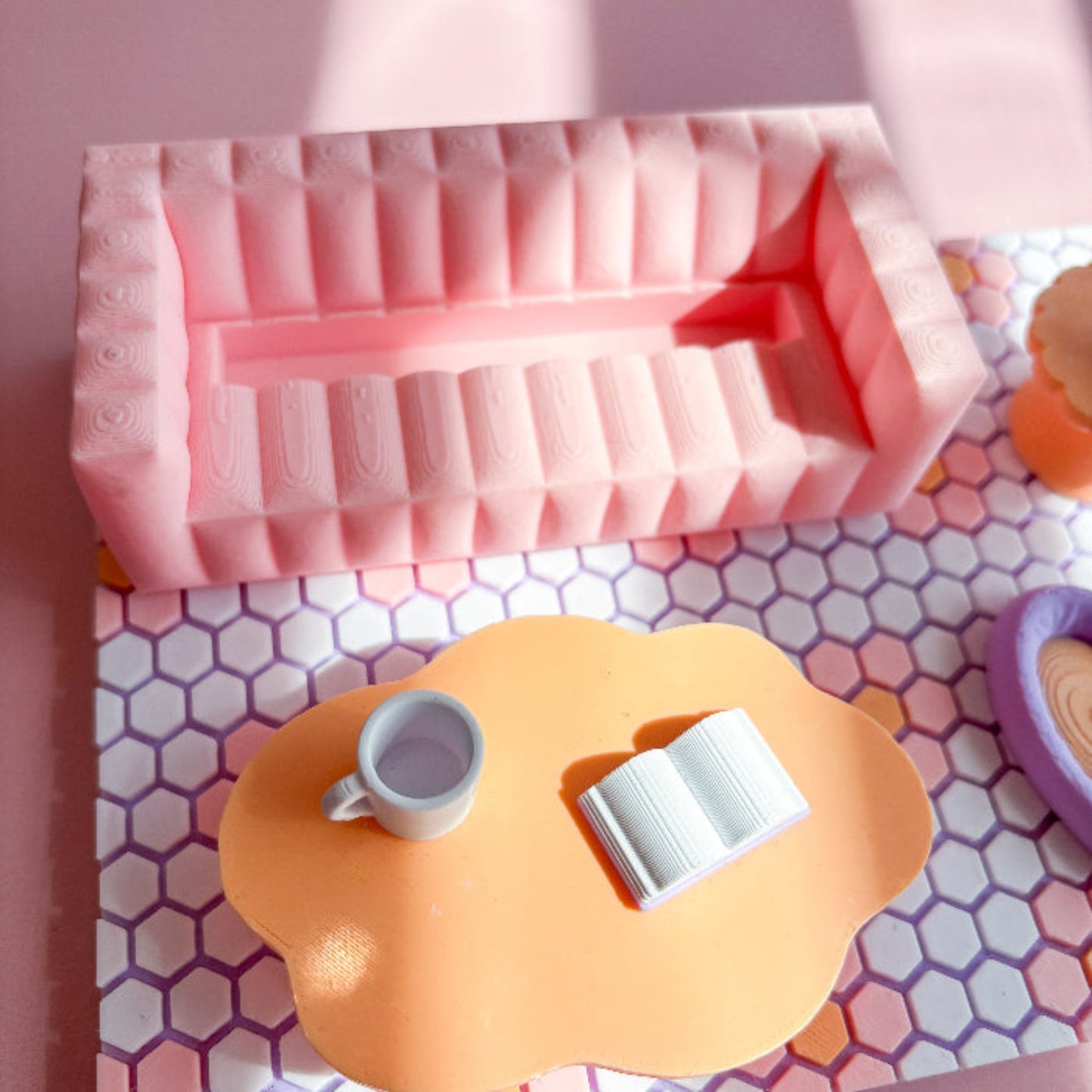 Pink silicone mold on a pink and white patterned surface with a small cup and book.