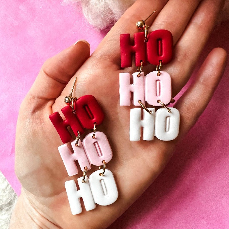 Light up the holiday season with these fun and festive "Ho Ho Ho" Dangle Earrings! Crafted from durable polymer clay, these earrings feature a bright and cheery palette of pink, red, and white to bring some festive flavor to your look. Get into the Christmas spirit with HO HO HO DANGLE EARRINGS!