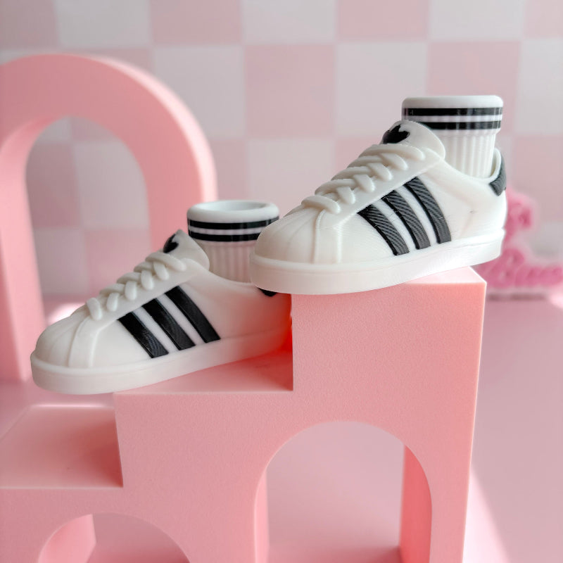 White sneakers fidget with black stripes on a pink geometric chair against a pink checkered background