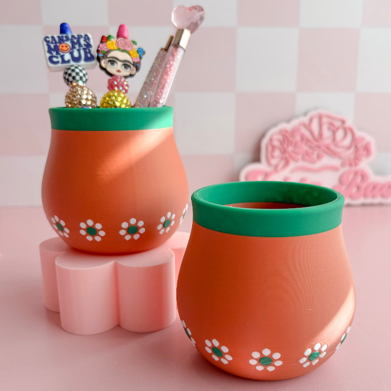 Two 3d Printed terracotta pots with green rims on a pink surface with decorative items.