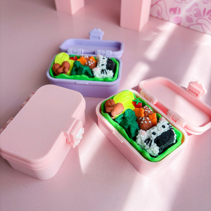 Pink and purple bento box fidgets with food on a pink surface