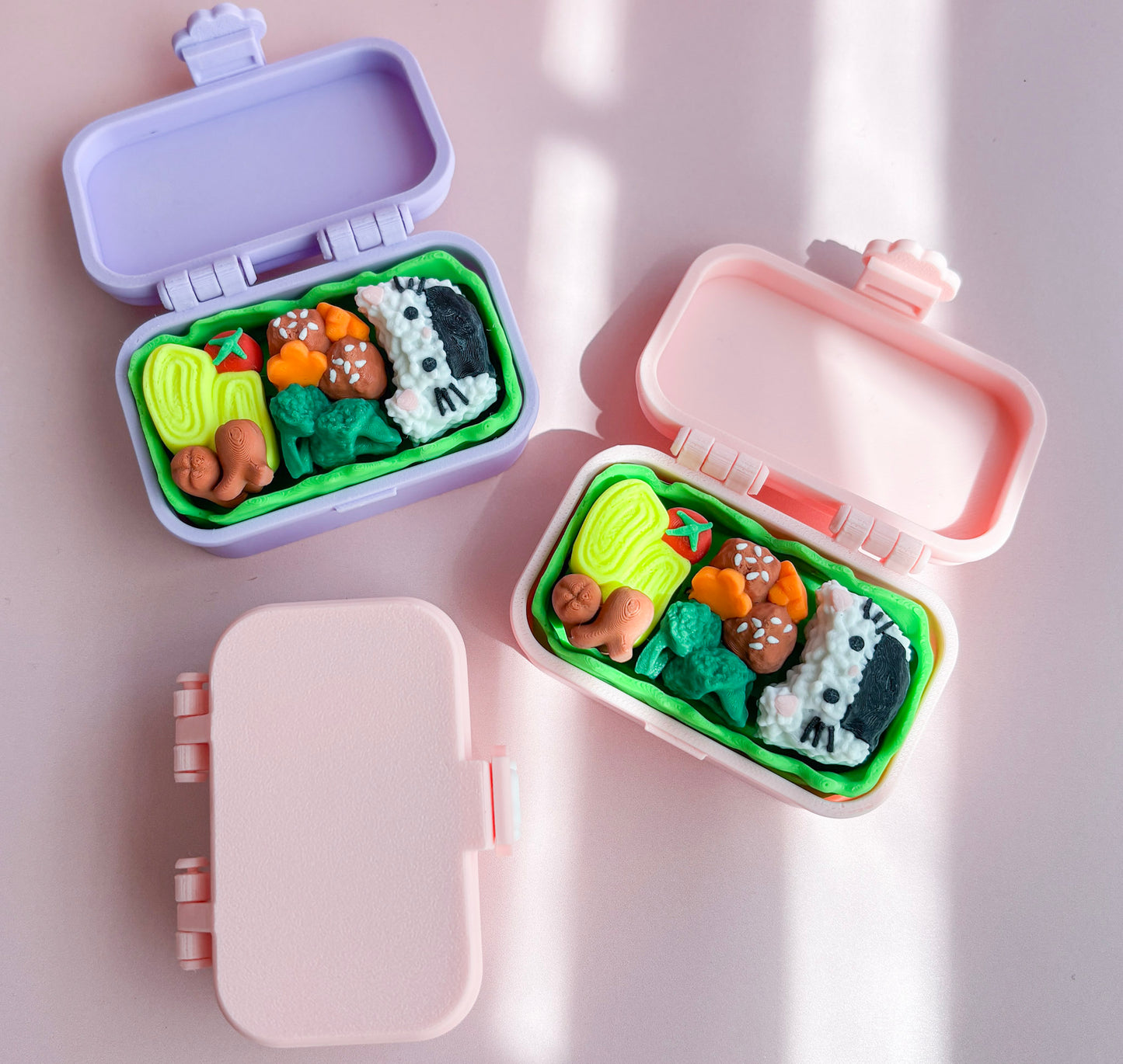 Pink and purple bento box fidgets with food on a pink surface