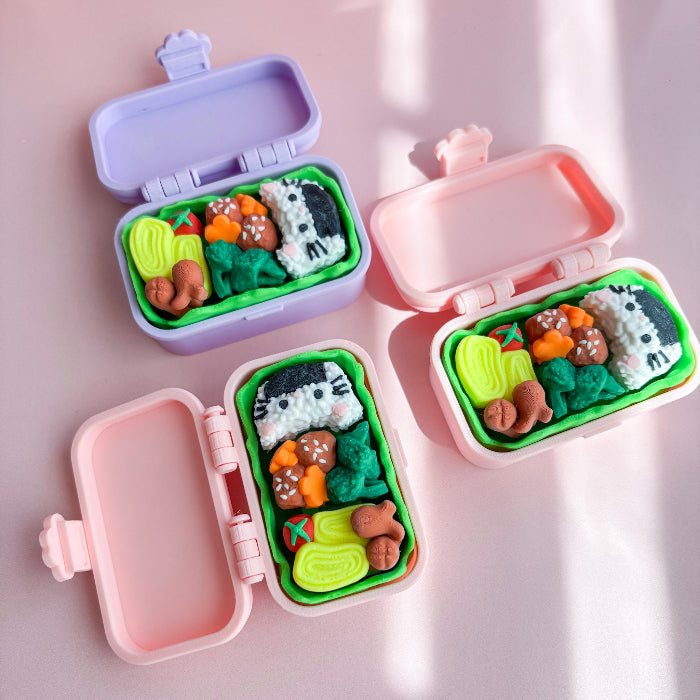 Pink and purple bento box fidgets with food on a pink surface