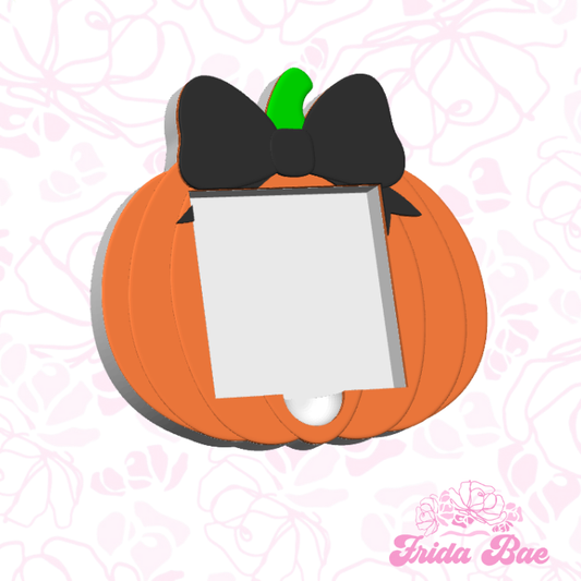 Pumpkin-shaped card holder with a black bow on a pink floral background