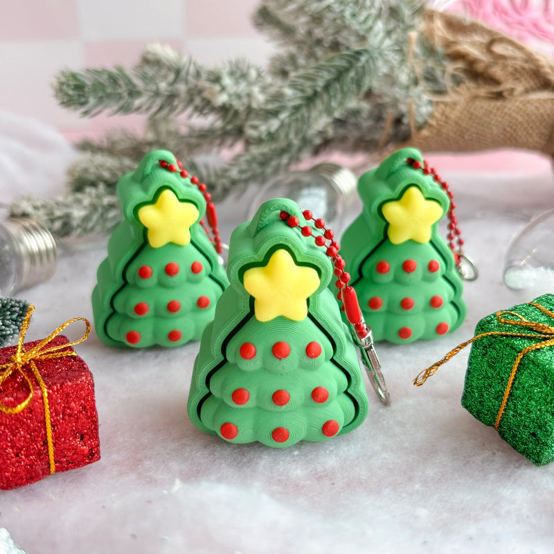Green Christmas tree-shaped fidget clicker ornaments with red dots and yellow stars on a decorative background.