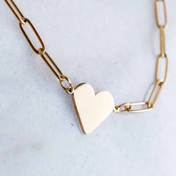 Fall in love with our Riri Heart Necklace in Gold! This elegant necklace features a polished finish and a heart-shaped charm on a unique paper clip chain. Personalize it with custom engraving for a meaningful touch. Add a touch of love to your wardrobe now! Pairs with our Nana Paperclip Heart Bracelet!