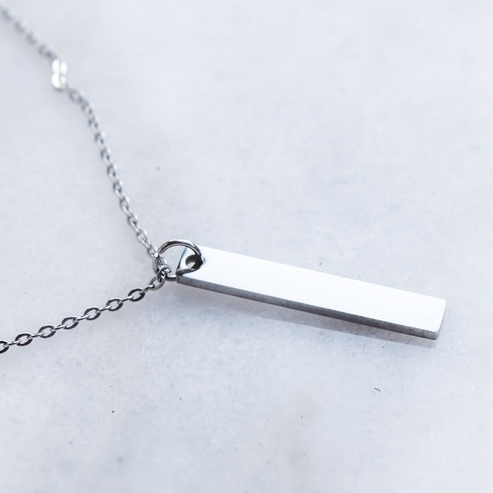 Add a touch of elegance to your everyday look with our Vertical Bar Pendant Necklace in Stainless Steel. Crafted from polished stainless steel, this lightweight necklace is perfect for daily wear and can be layered with other pieces. Its minimalistic design can also be engraved for a unique and personalized touch.