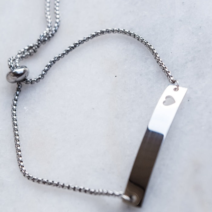 This polished heart bar bracelet is the perfect symbol of love. Its adjustable chain fits a wide range of wrist sizes, making it a versatile and timeless piece. The heart-shaped cutout adds an extra touch of warmth and affection, making it a cherished piece in anyone's jewelry collection.