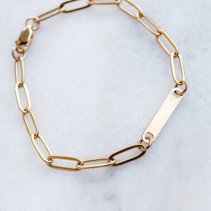 Elevate your style with our 1-Bar Paperclip Chain Bracelet in gold. This fully customizable necklace features a sleek design and can be laser engraved in your choice of font. Make a statement and stand out from the crowd with this unique and personalized piece.