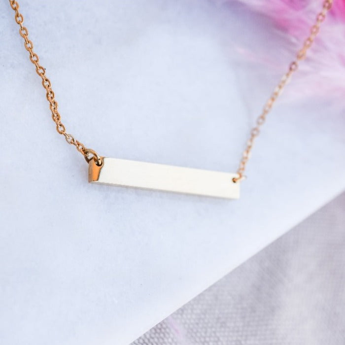 Elevate your style with our Bar Necklace in gold. Made with a sleek, polished bar pendant on an 18" chain, you can personalize it with engraved or stamped words, names, or dates. Minimalist design for a chic and personalized touch. Layer with other chains for a unique look.