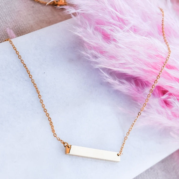 Elevate your style with our Bar Necklace in gold. Made with a sleek, polished bar pendant on an 18" chain, you can personalize it with engraved or stamped words, names, or dates. Minimalist design for a chic and personalized touch. Layer with other chains for a unique look.