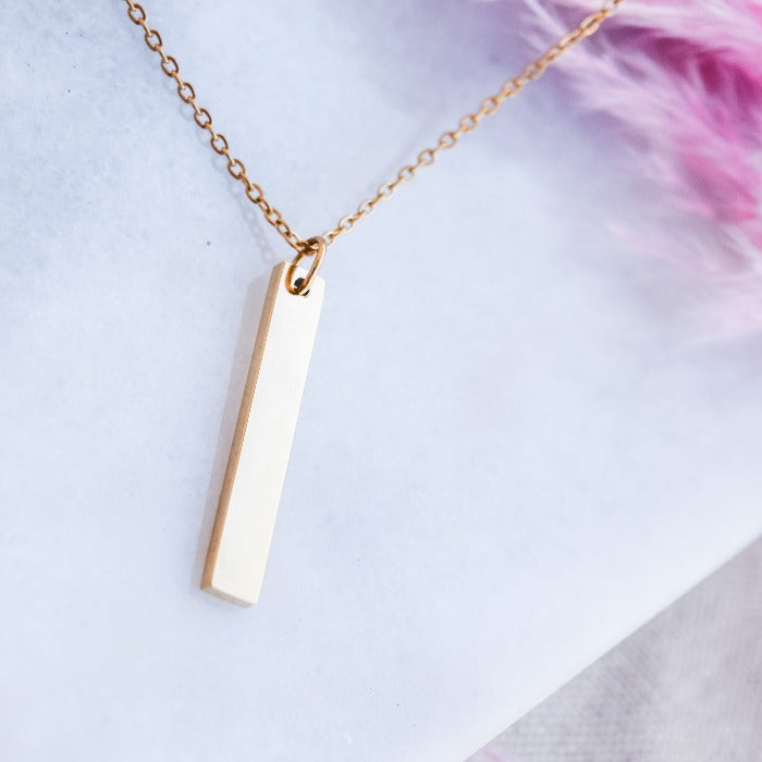 Add a touch of elegance to your everyday look with our Vertical Bar Pendant Necklace in Gold. Crafted from polished stainless steel, this lightweight necklace is perfect for daily wear and can be layered with other pieces. Its minimalistic design can also be engraved for a unique and personalized touch.