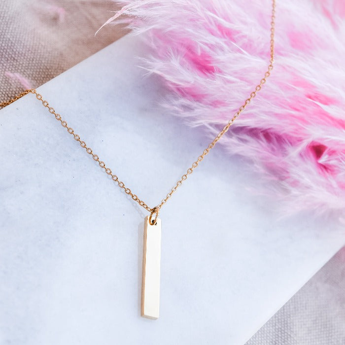 Add a touch of elegance to your everyday look with our Vertical Bar Pendant Necklace in Gold. Crafted from polished stainless steel, this lightweight necklace is perfect for daily wear and can be layered with other pieces. Its minimalistic design can also be engraved for a unique and personalized touch.