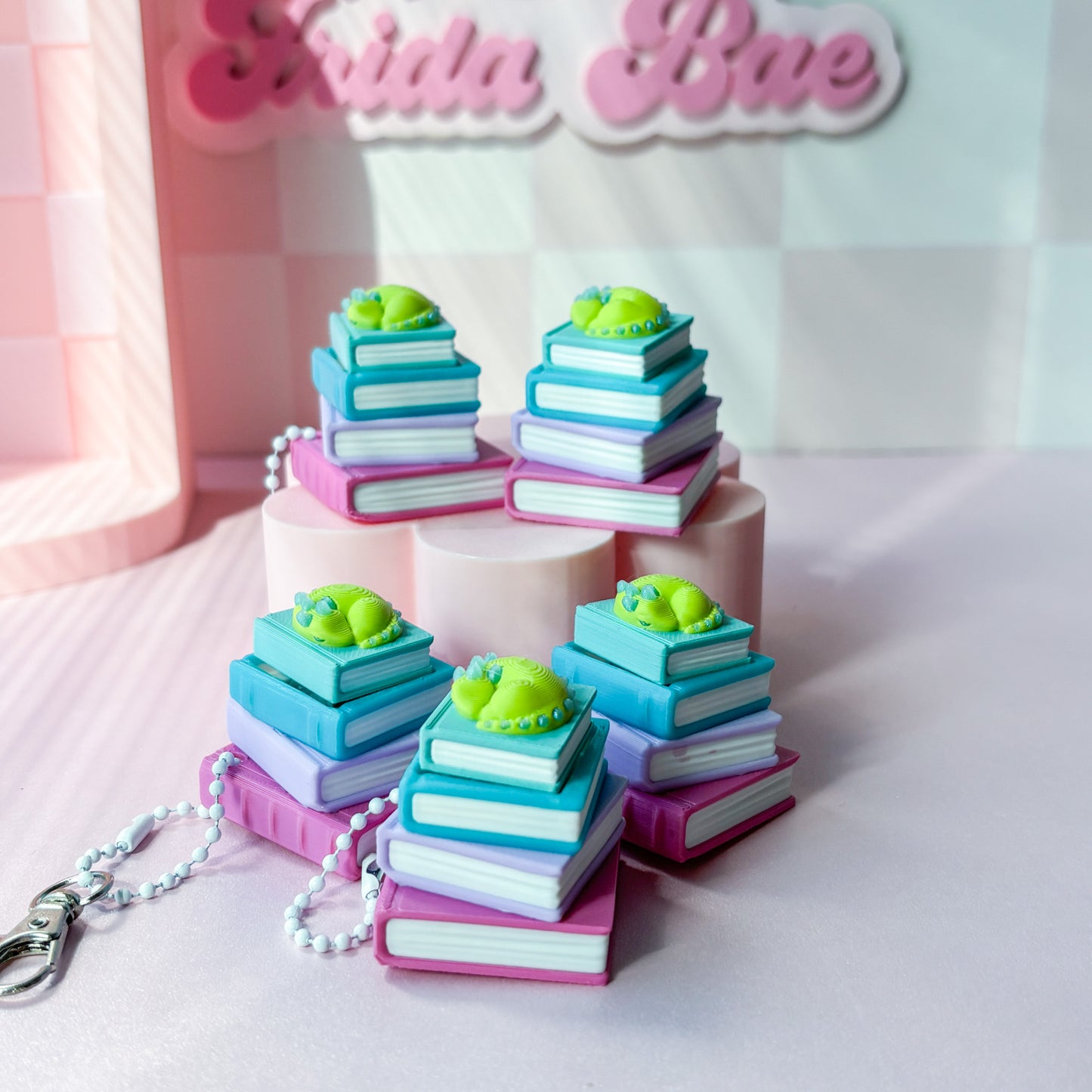 stack of colorful books with green dragon on top on pink background
