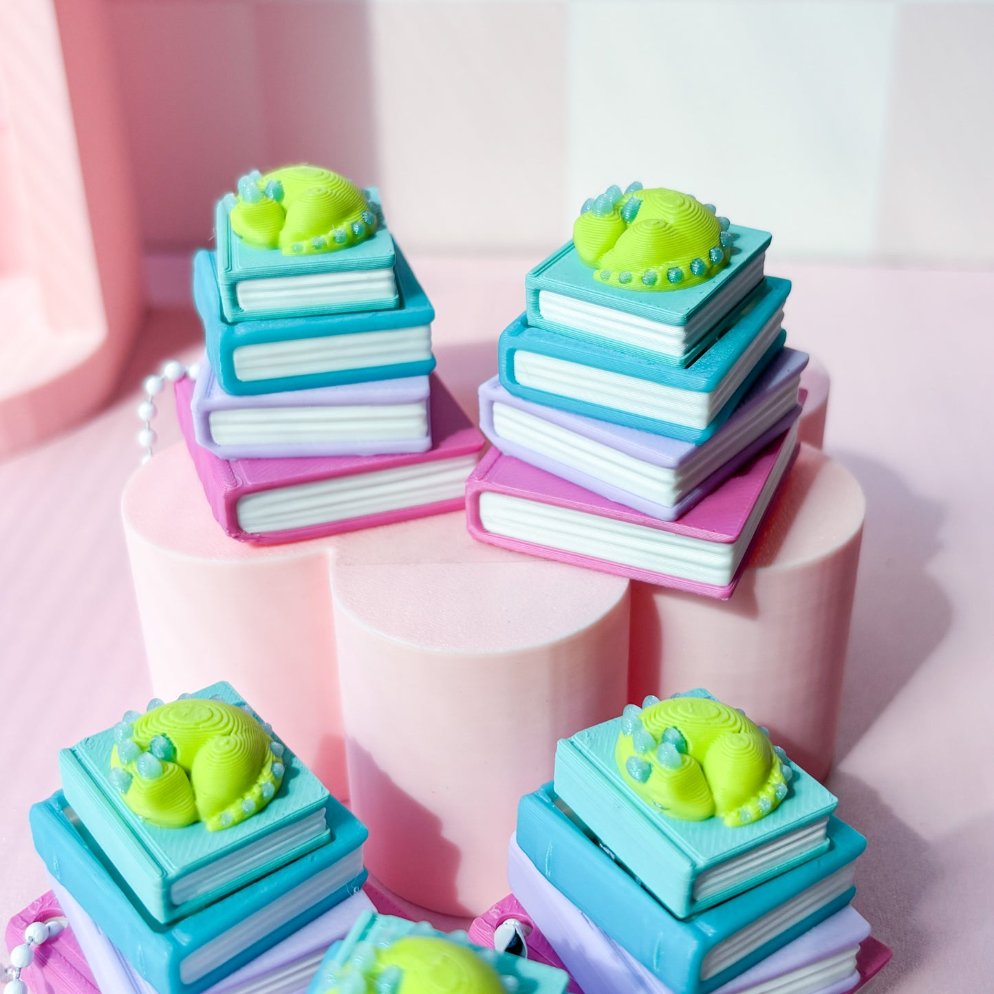 stack of colorful books with green dragon on top on pink background