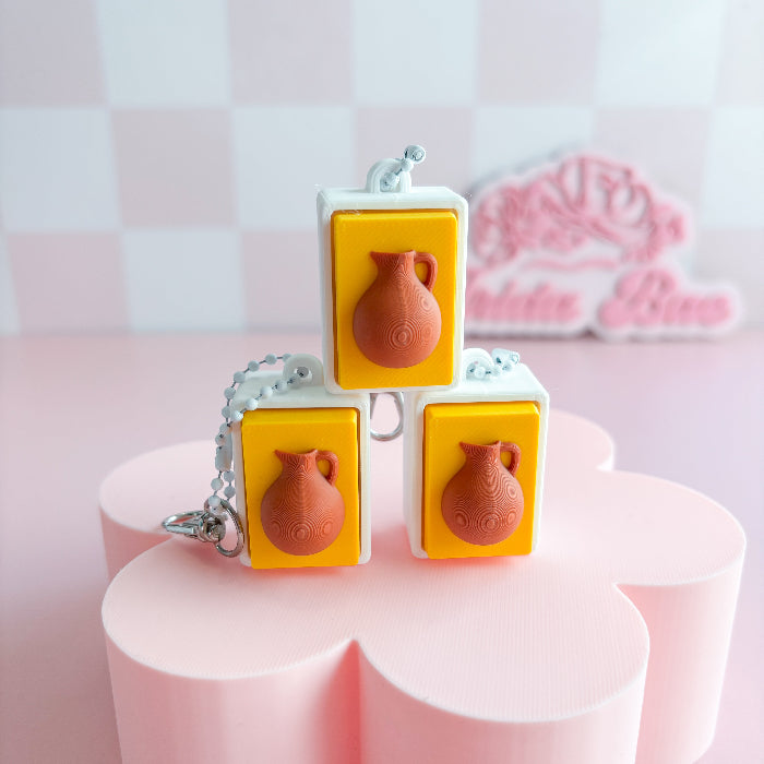 Mexican fidget clicker with terracotta-colored pots on a pink stand with a checkered background