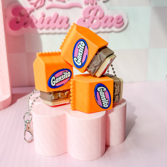 Gansito candy-themed keychains on pink stands with a blurred background