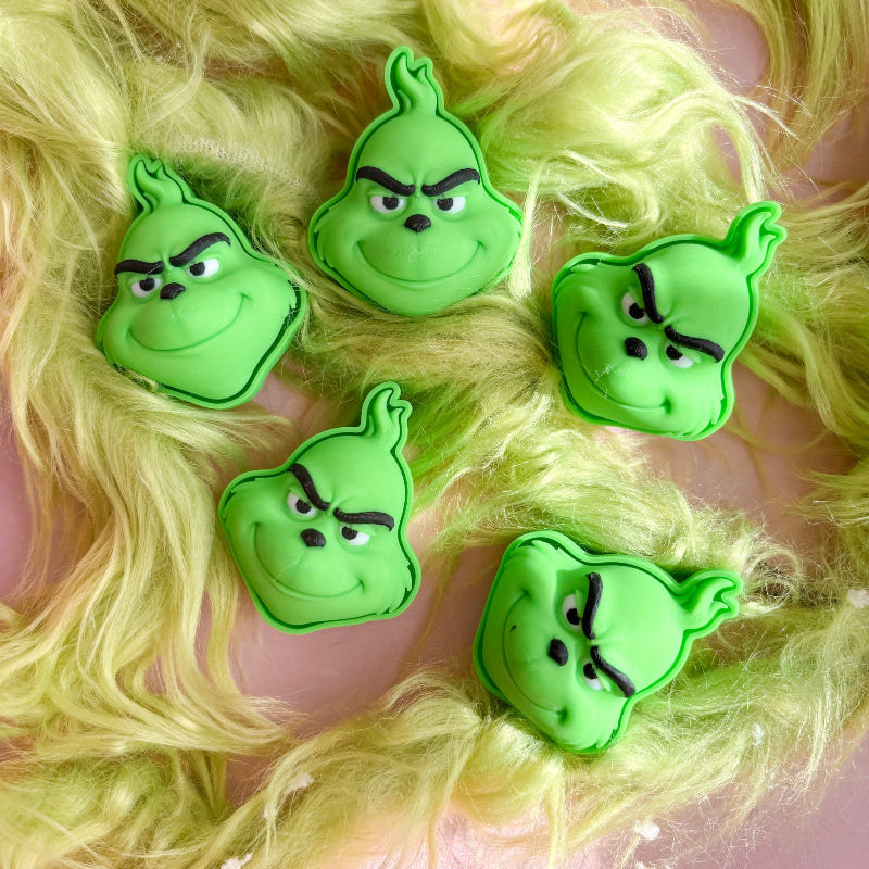 Green character-shaped fidget clicker on a fluffy yellow background