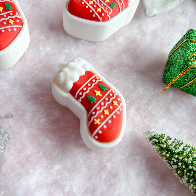 Decorative Christmas fidget clicker items on a textured surface with a snowy background.