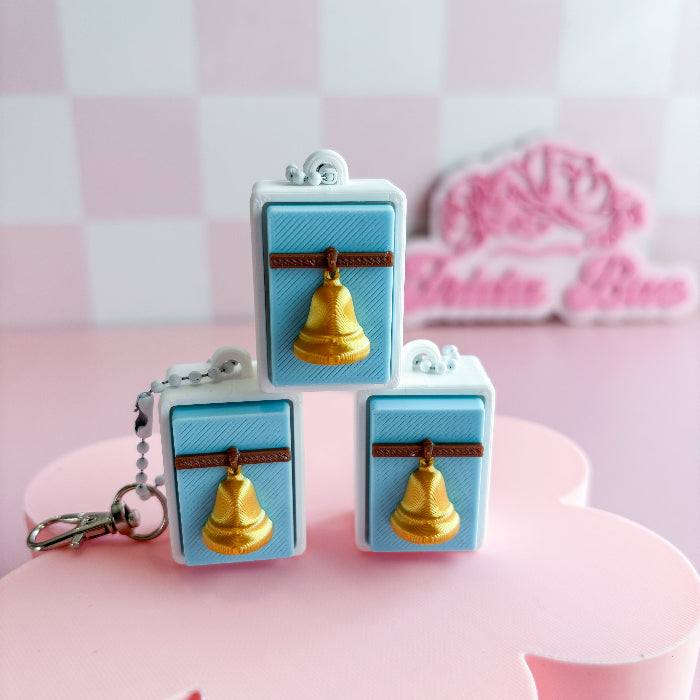 Mexican loteria fidget clicker gold bells on a pink surface