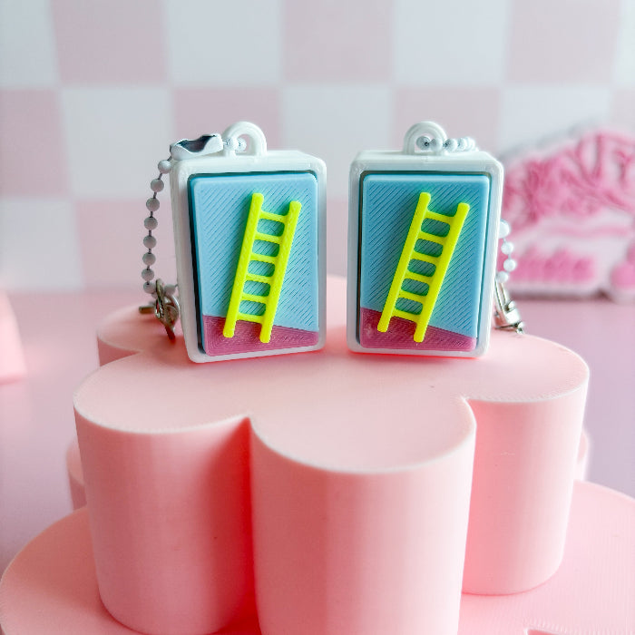 Mexican loteria fidget clicker with a ladder design on a pink stand against a pink checkered background