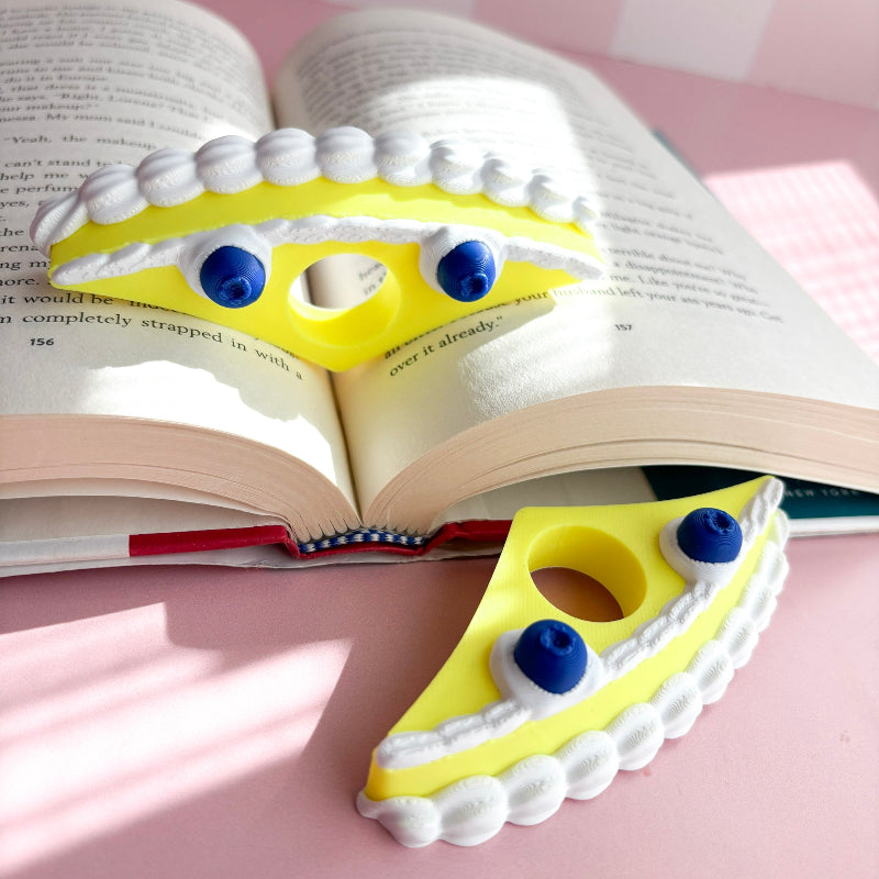 Yellow book holder with blueberries in an open book against a pink checkered background