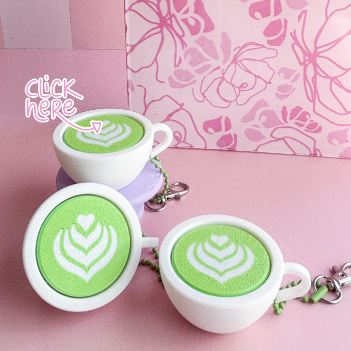 White ceramic cups with green latte art on a pink background
